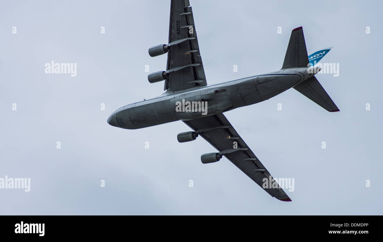 Antonov 124-100 UR-82073 jumbo jet cargo transporter plane flying underbelly landing lights on flaps down cloudy sky Stock Photo