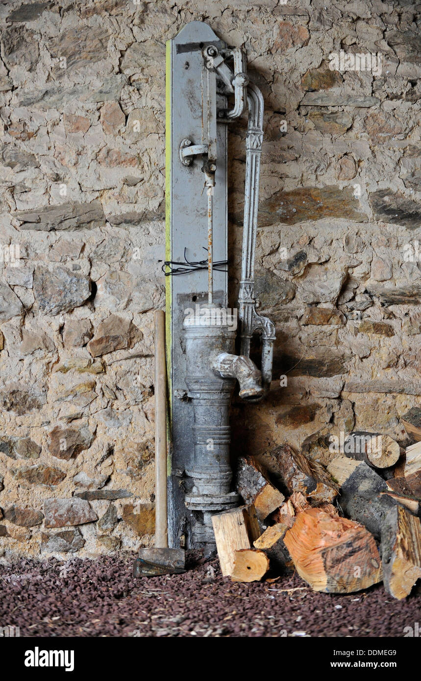 Old French water hand pump inside a stone built barn. Stock Photo