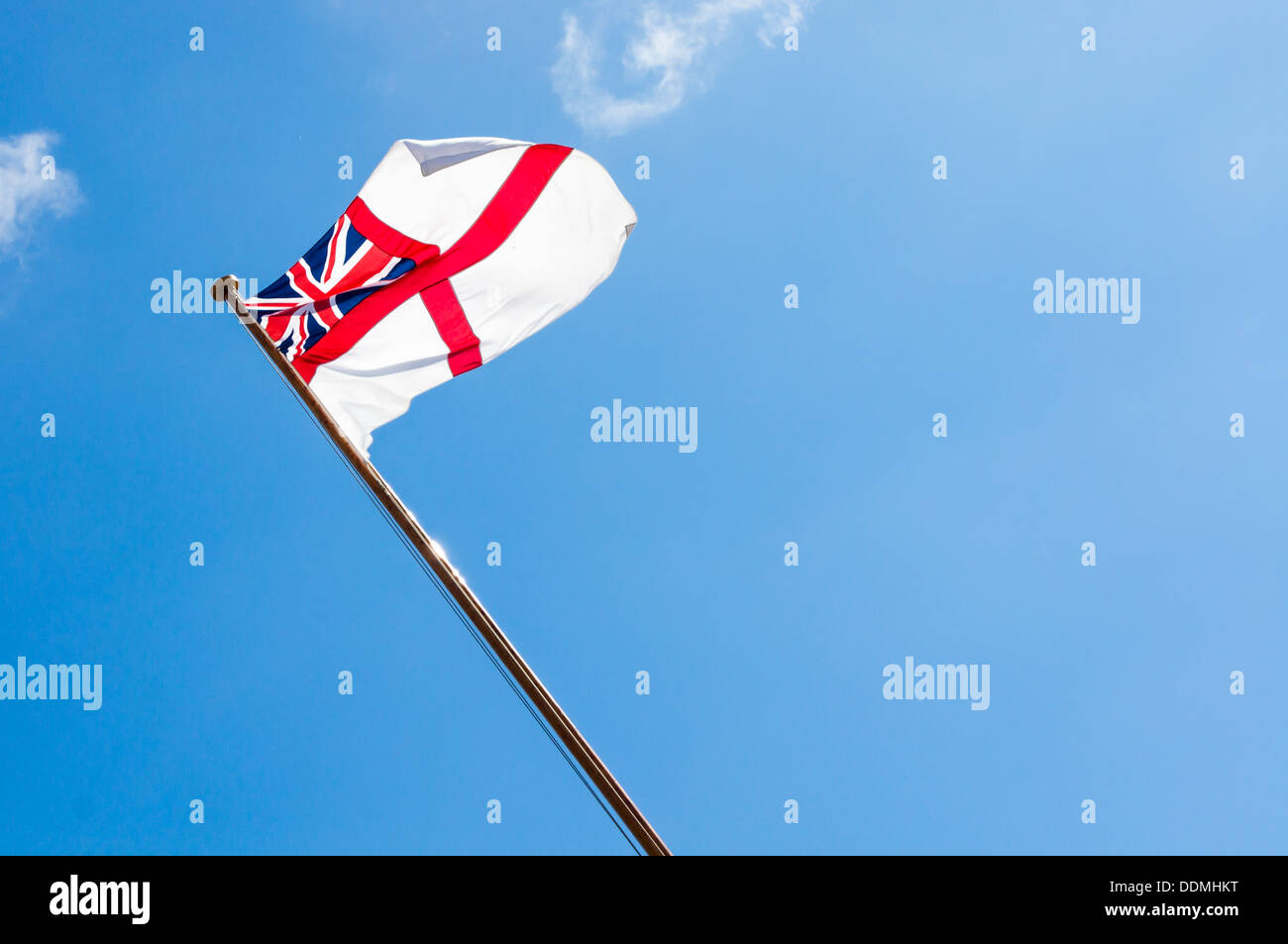 Royal Navy White ensign flies against a blue sky Stock Photo