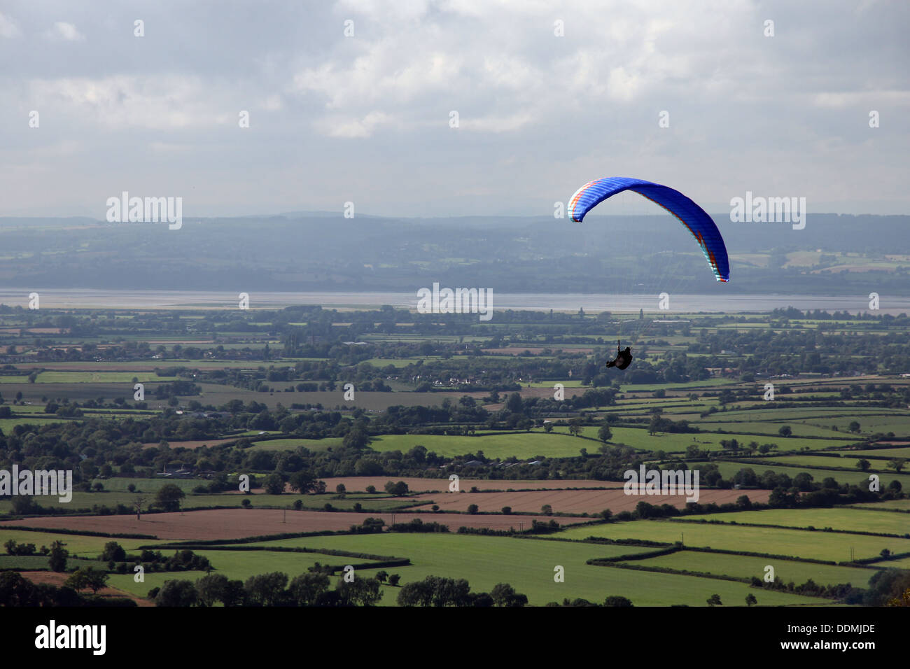 A paraglider rises above the Cotswold escarpment at Woodchester, Cheltenham, UK. Stock Photo