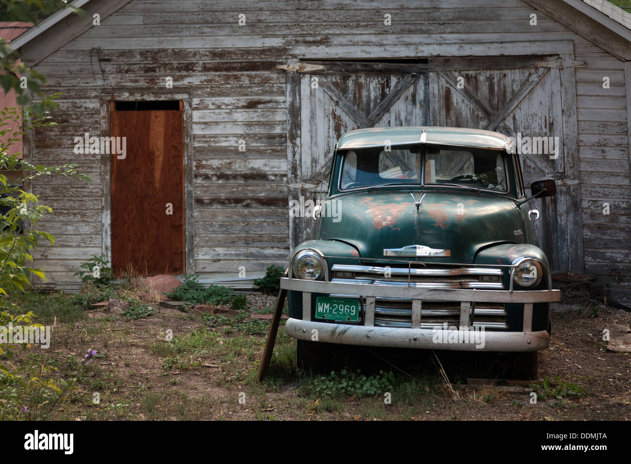 Old and abandoned Chevrolet pick up truck, parked outside a run down garage, Colorado, USA Stock Photo