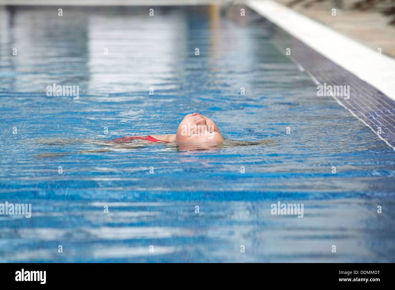little girl learning to swim the backstroke in outdoor swimming pool