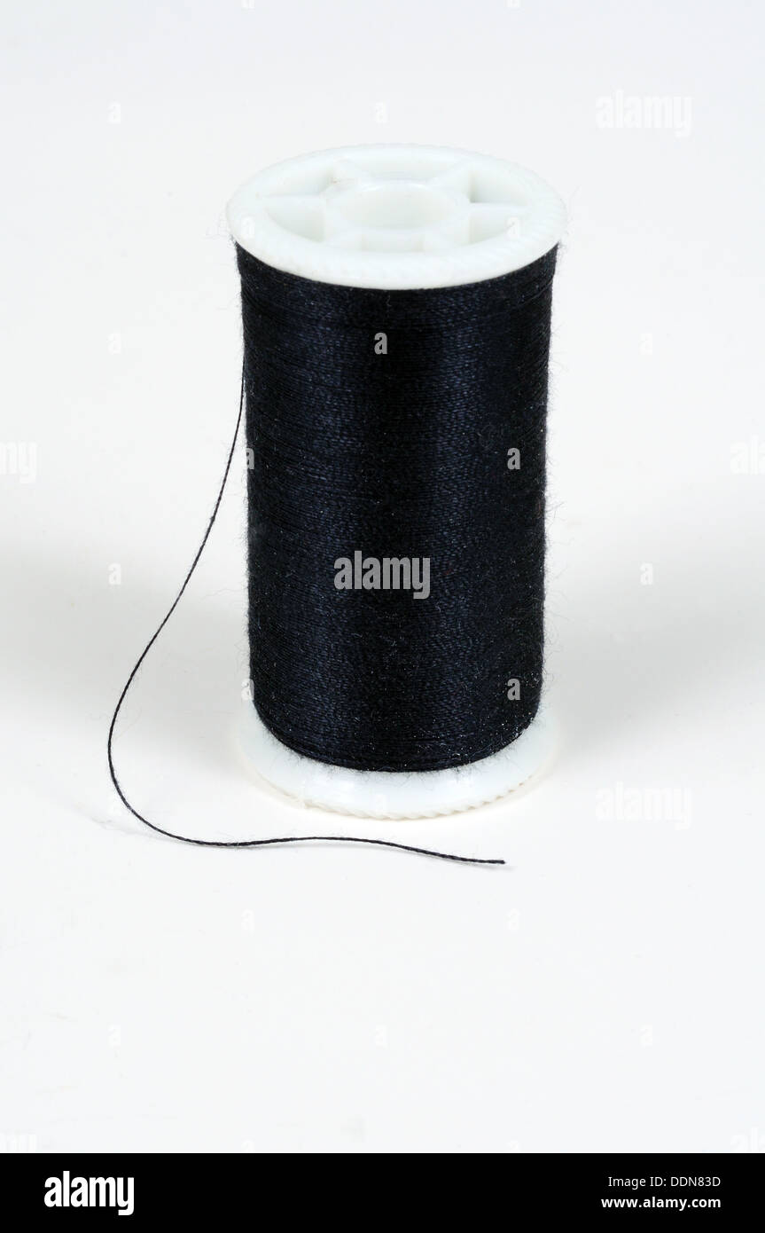 Spool of black cotton against a white background Stock Photo - Alamy