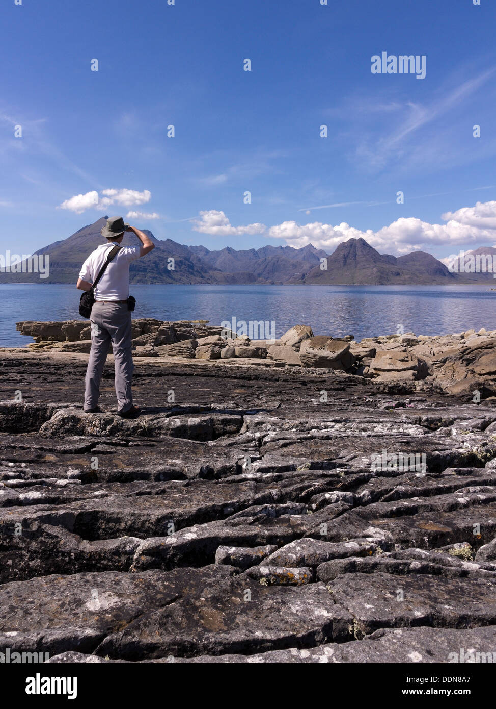 Male holidaymaker admiring view from Elgol over Sea Loch Scavaig to the Black Cuillin mountains, Isle of Skye, Scotland, UK Stock Photo