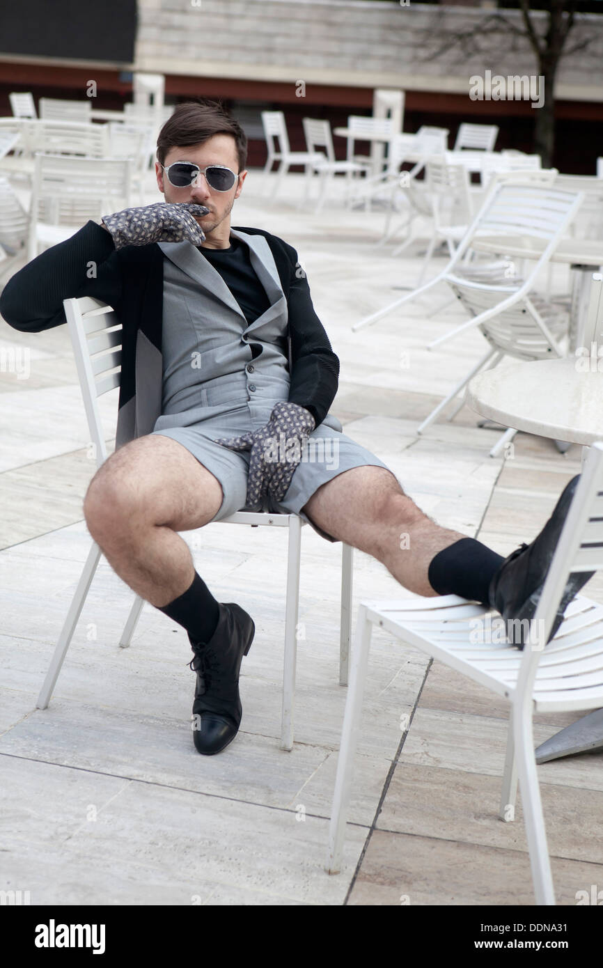 cheeky young man in fashionable glasses wearing grey shorts with hairy legs  sitting on chair at street cafe Stock Photo - Alamy