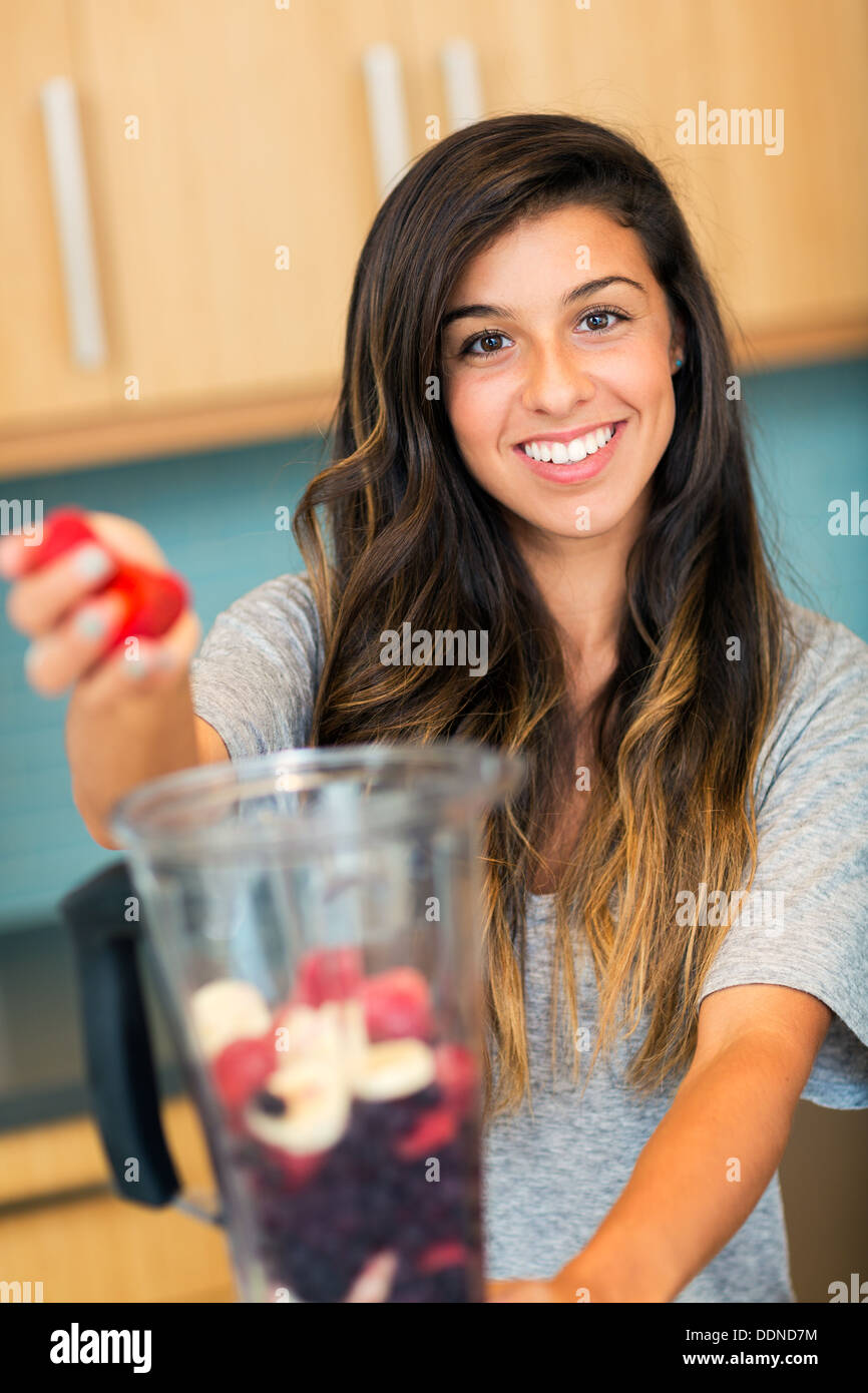 Beautiful Young Woman Making Fruit Smoothie in Blender Stock Photo