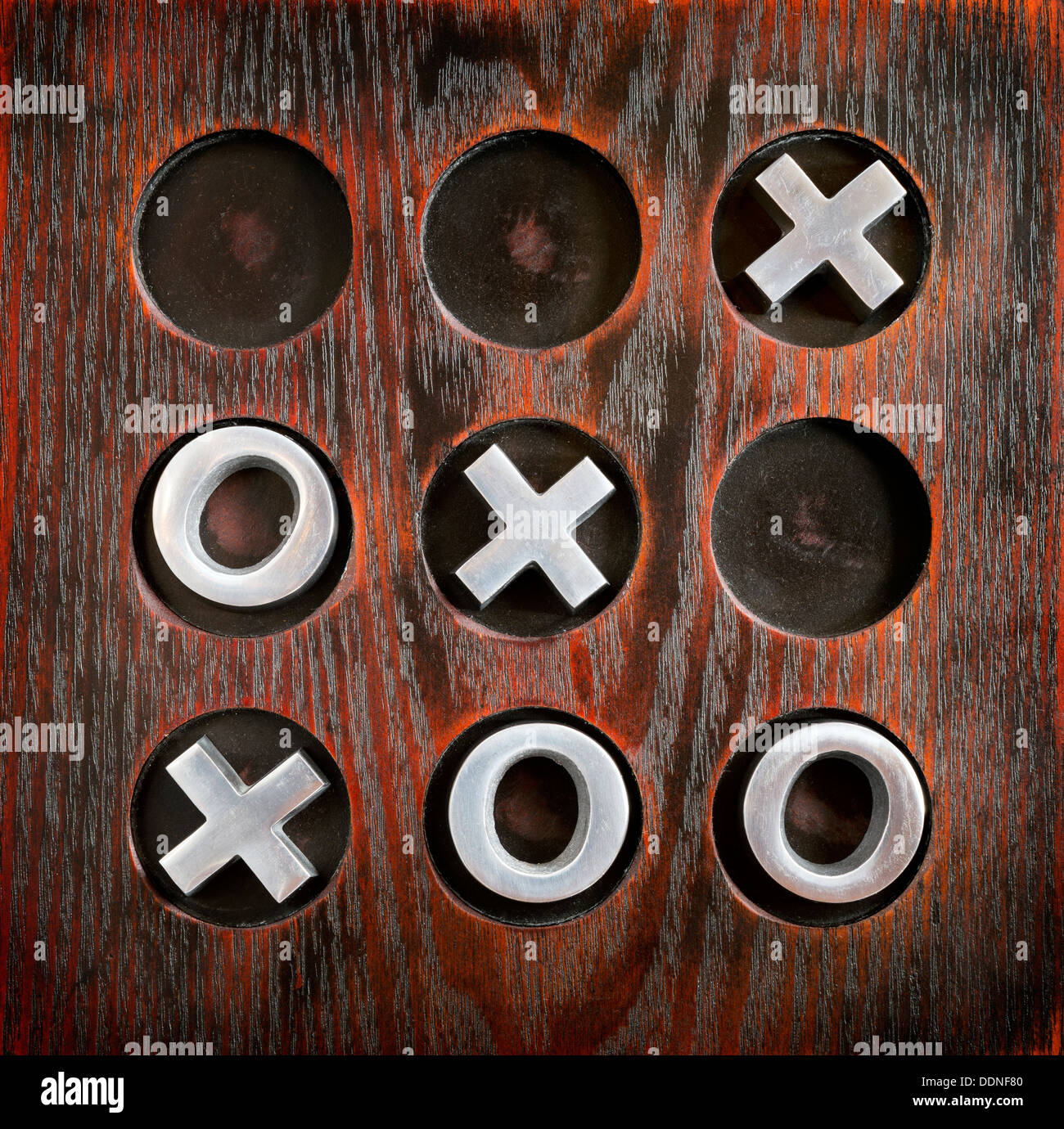 Game of Tic Tac Toe or Noughts and Crosses on a wooden board with metal pieces Stock Photo
