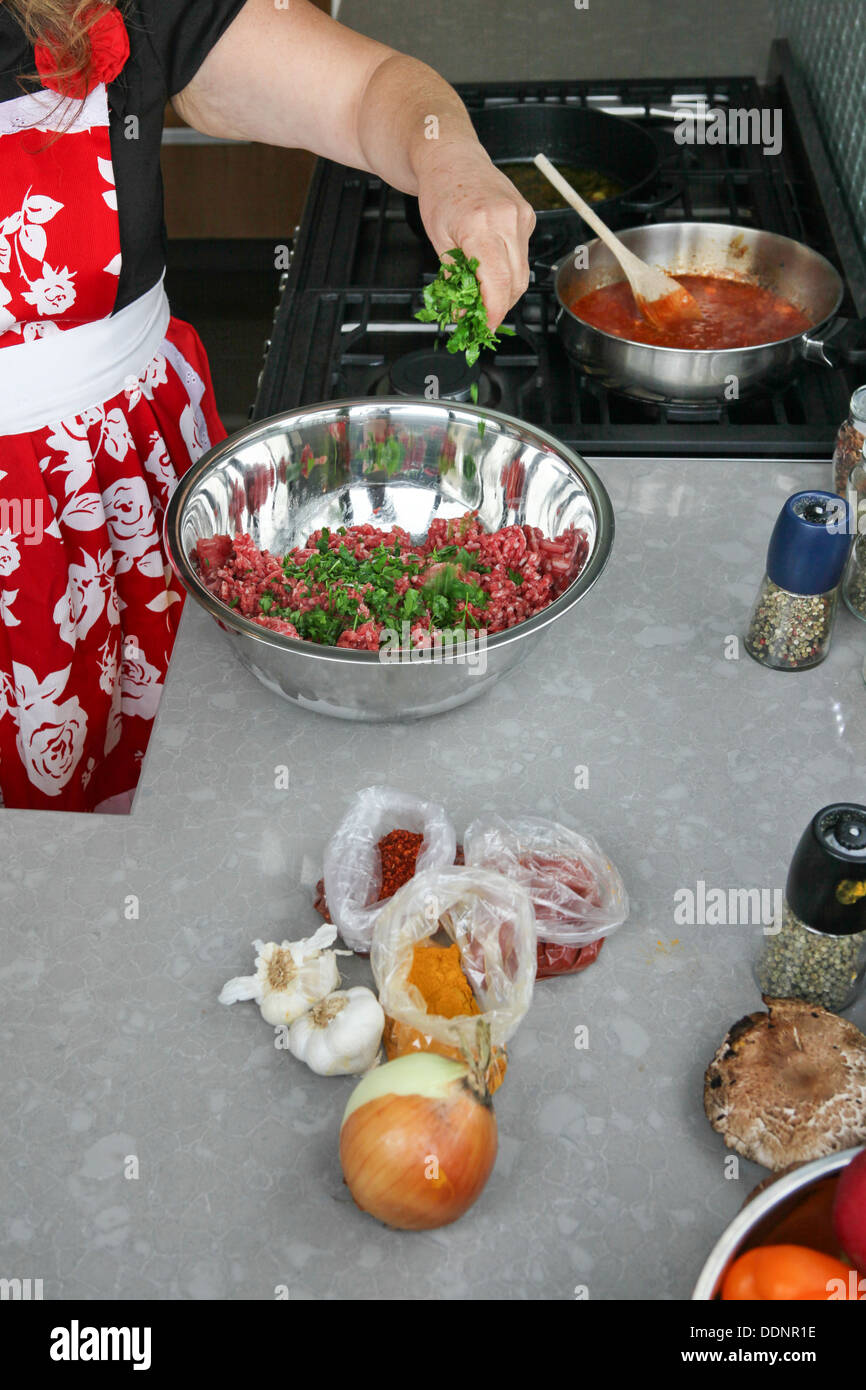 Cooking Moroccan meatballs in tomato sauce adding herbs to the minced meat Stock Photo