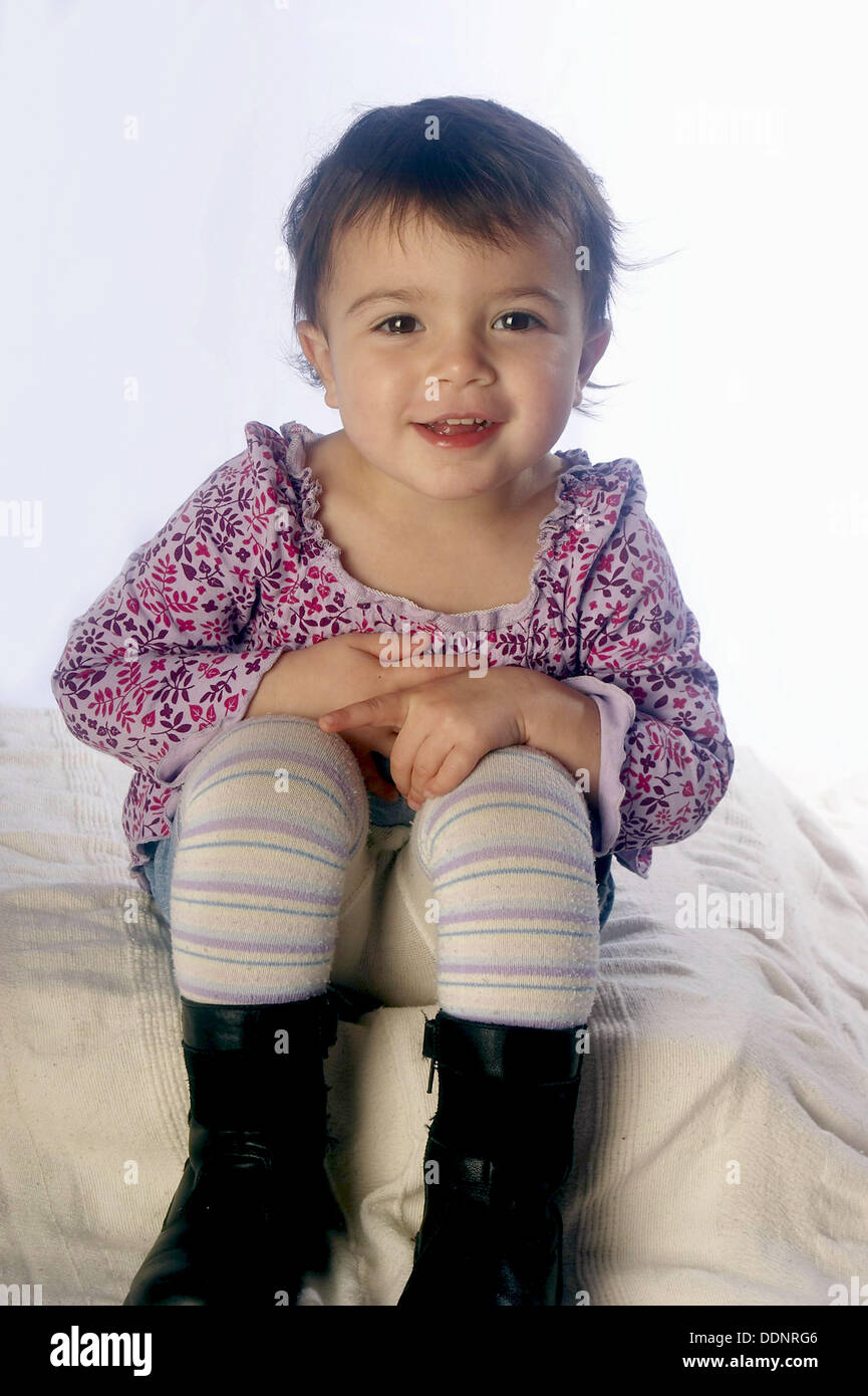 2 year old girl sitting on the floor, smiling into camera,studio Stock ...