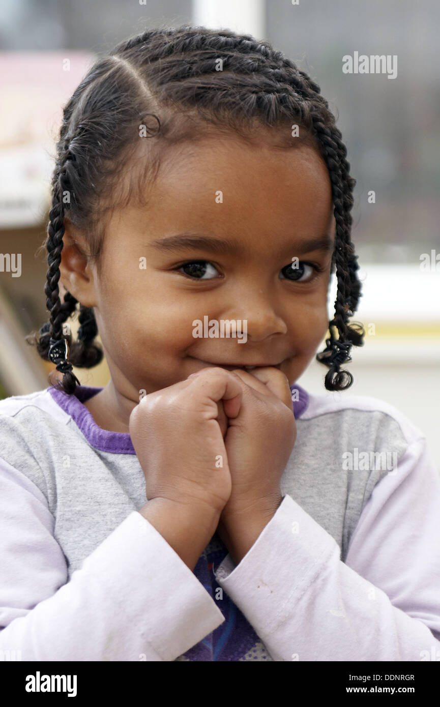 3 year old black girl playing at nursery, smiling into camera, with braids  in her hair and her hands up to her face Stock Photo - Alamy