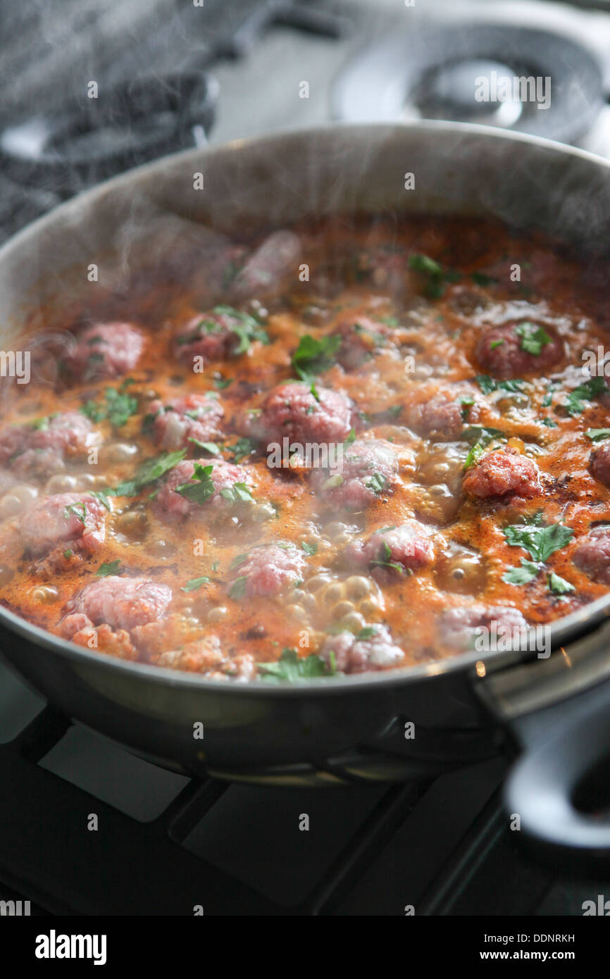 Cooking Moroccan meatballs in tomato sauce Meatballs cook in a pot Stock Photo