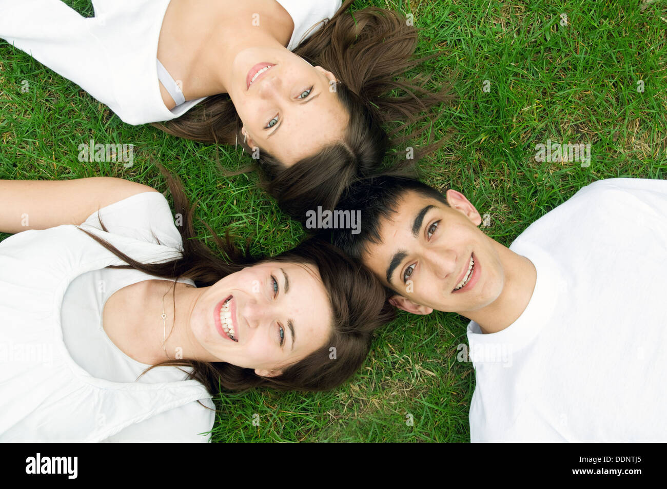 Three young happy friends lying down together Stock Photo