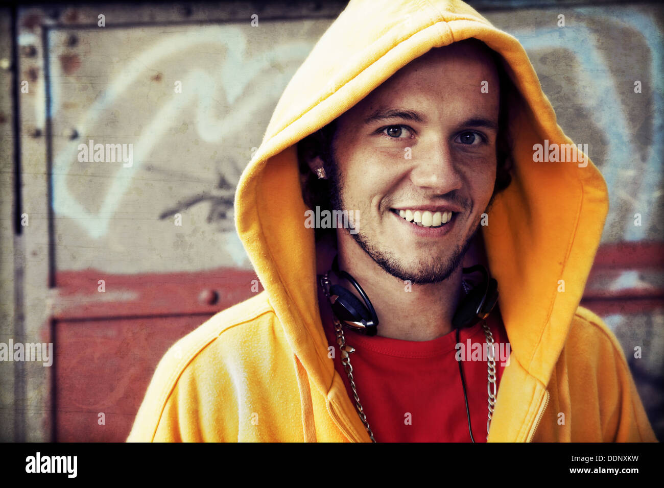Teen / Young man portrait in hooded sweatshirt / jumper on grunge graffiti wall Stock Photo