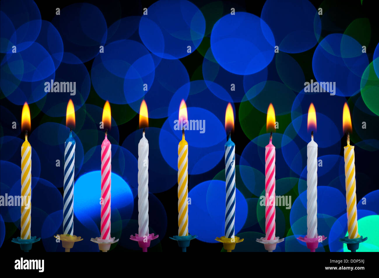 Birthday colour candles with fire on blue background Stock Photo - Alamy