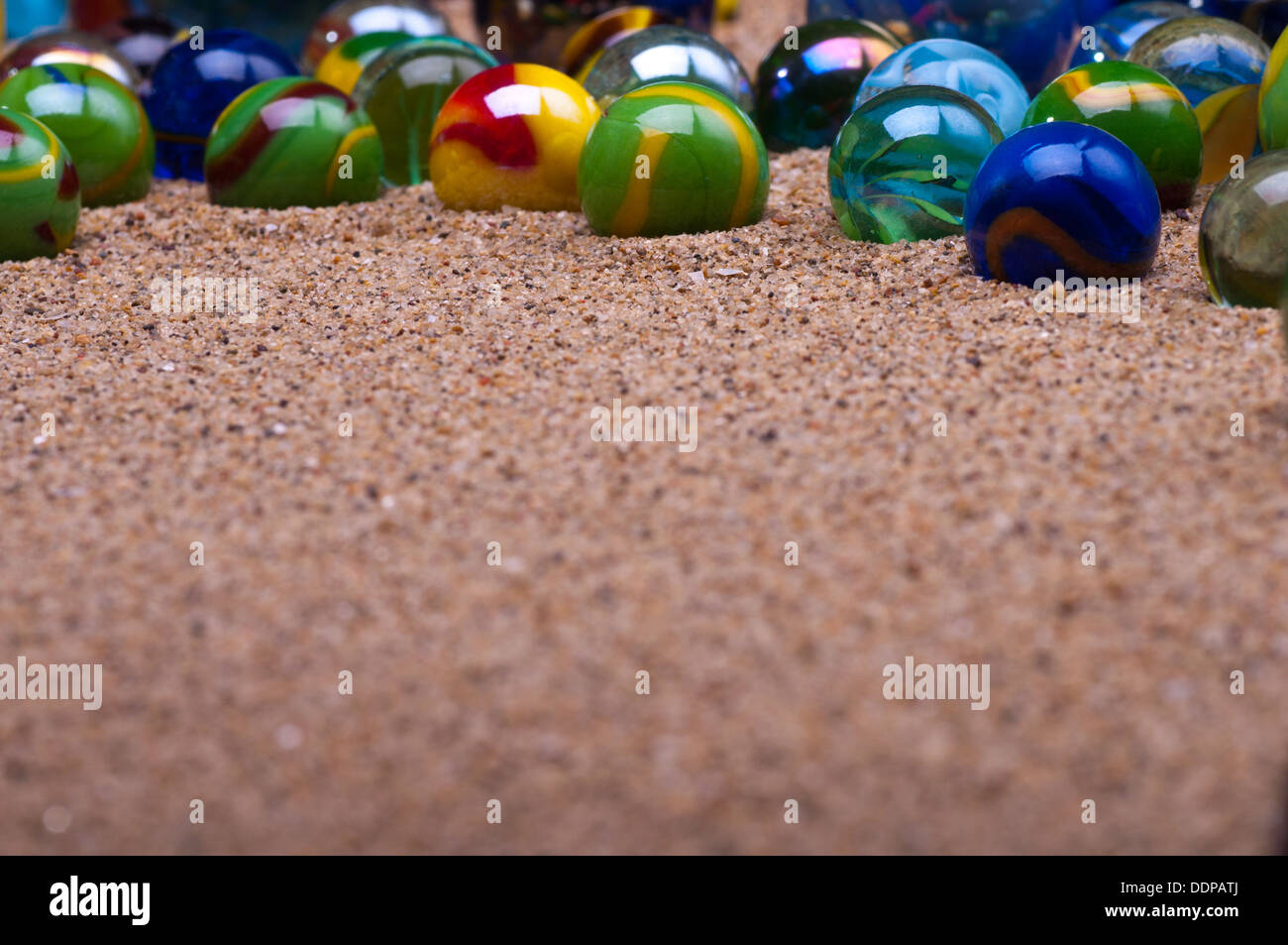 Colored glass marbles on a sandy background Stock Photo Alamy