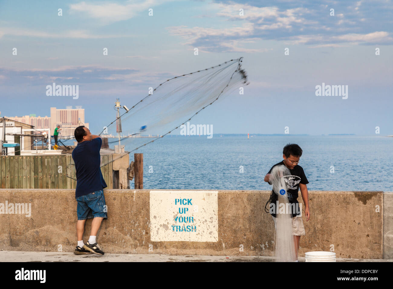 Man and son fishing for shrimp by throwing cast nets from the Small Craft  Harbor in Biloxi, Mississippi Stock Photo - Alamy