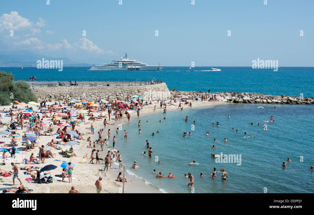 A packed Antibes beach on the French Riviera Cote d’Azur with Roman Abramovich's super yacht Eclipse in the background, France Stock Photo