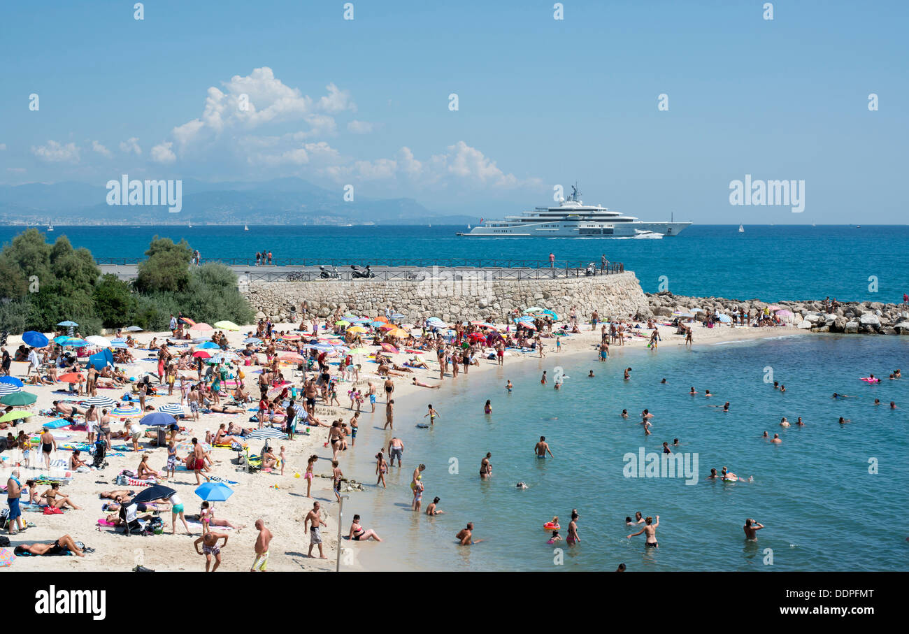 A packed Antibes beach on the French Riviera Cote d’Azur with Roman Abramovich's super yacht Eclipse in the background, France Stock Photo