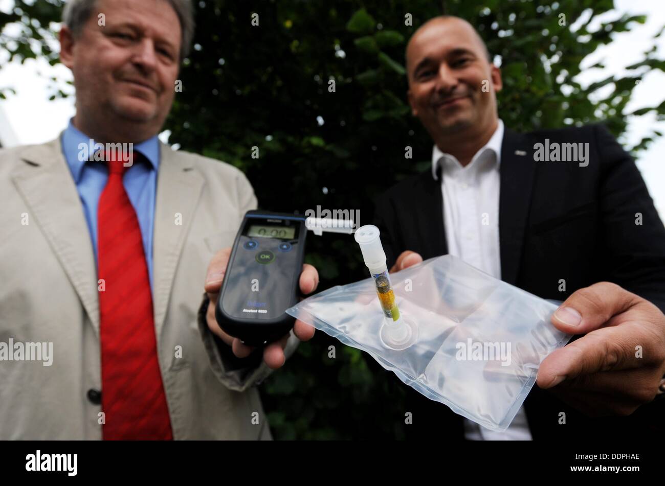 Product manager Juergen Sohege (L) and project manager Mirco Spitzbarth demonstrate first generation (L) and current model (R) portable alcohol testing devices made by the Draeger company in Luebeck, Germany, 22 August 2013. For 60 years, Draeger has been providing alcohol testing devices all over the world. Photo: Carsten Rehder Stock Photo