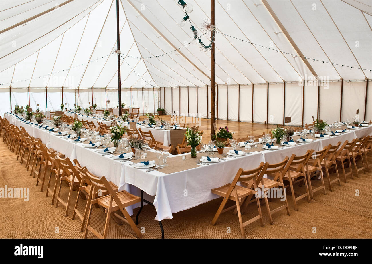 Interior of a marquee at a large wedding, with tables laid ready for lunch, UK Stock Photo