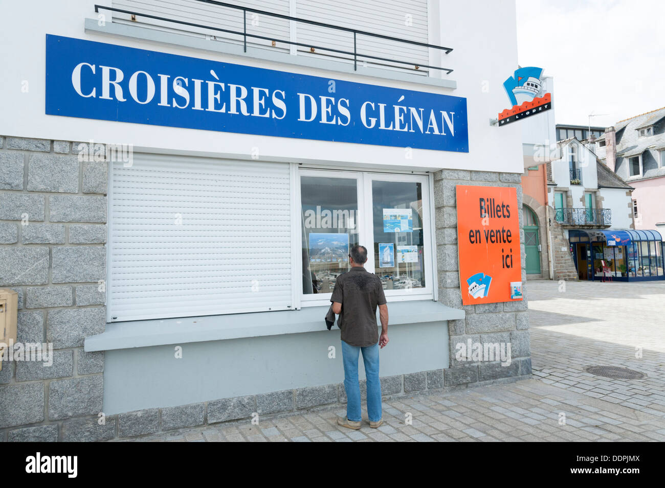 Man looking in the window of a shop selling cruises to the Isles of Glenan Concarneau Brittany France Stock Photo