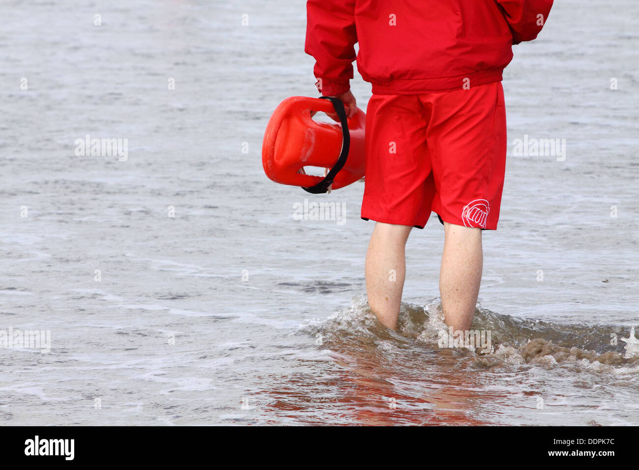 Lifeguard with rescue buoy standing in the sea at Enniscrone beach, Ireland Stock Photo