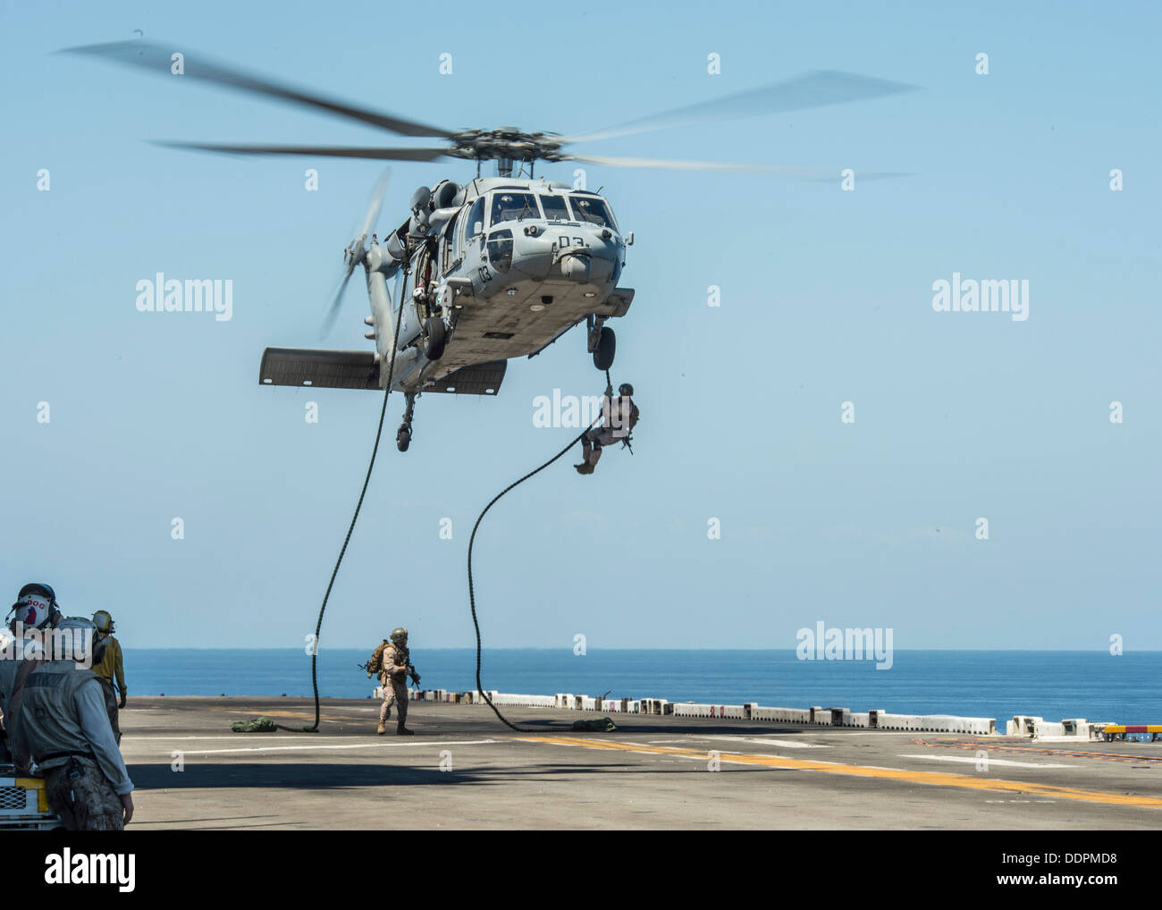 Marines assigned to the 31st Marine Expeditionary Unit (MEU) fast-rope from an MH-60S Sea Hawk to the flight deck of forward-deployed amphibious assault ship USS Bonhomme Richard (LHD 6) during a training exercise. Bonhomme Richard is the flagship of the Stock Photo