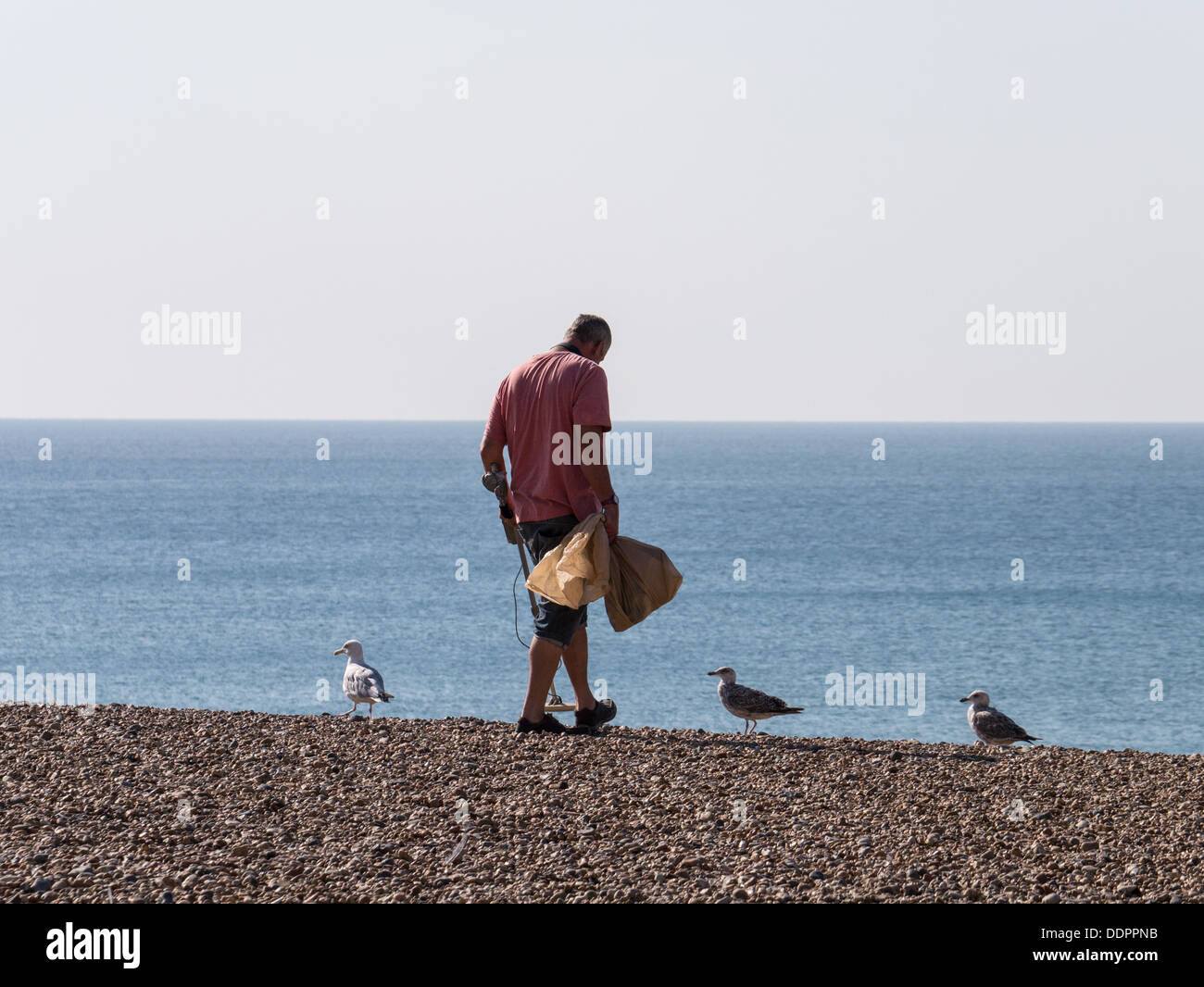 A man searches for treasure on the beach with a metal detector Stock Photo