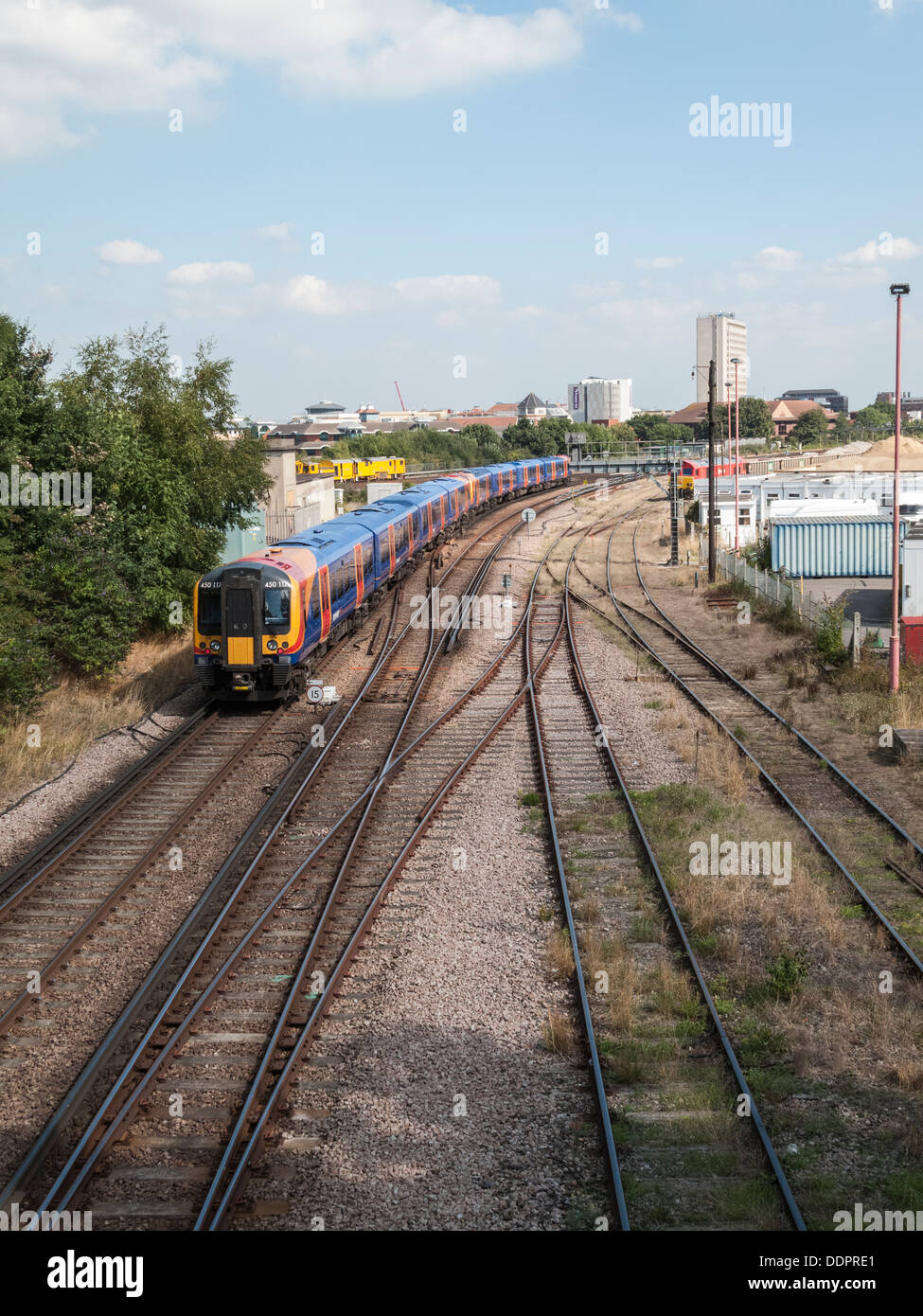 Railway tracks leading towards Woking, Surrey, England with South West Trains passenger train approaching Woking station Stock Photo