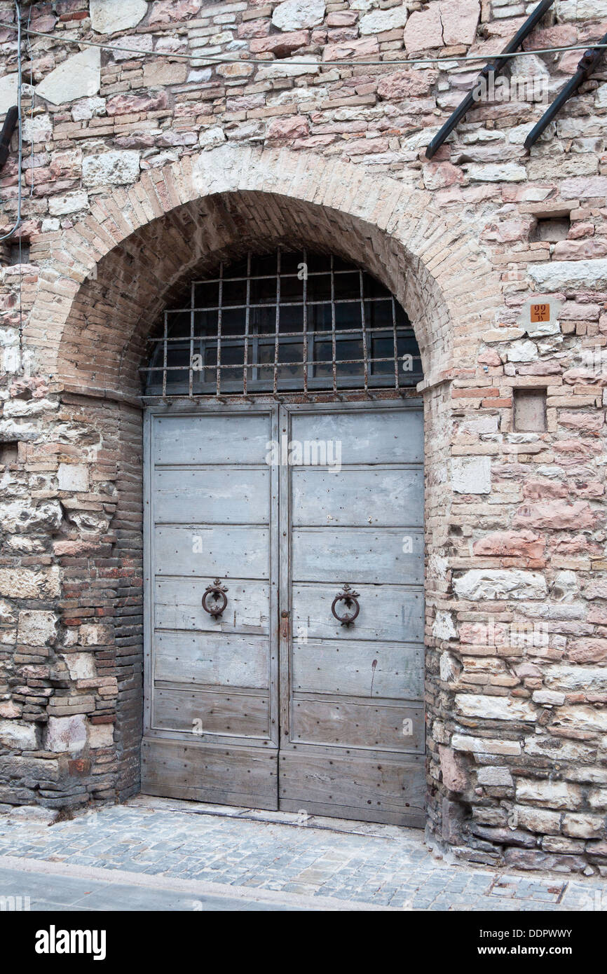 View of old double wooden arched door of stone medieval palace, with wrought iron grille window, and traditional wrought iron ti Stock Photo