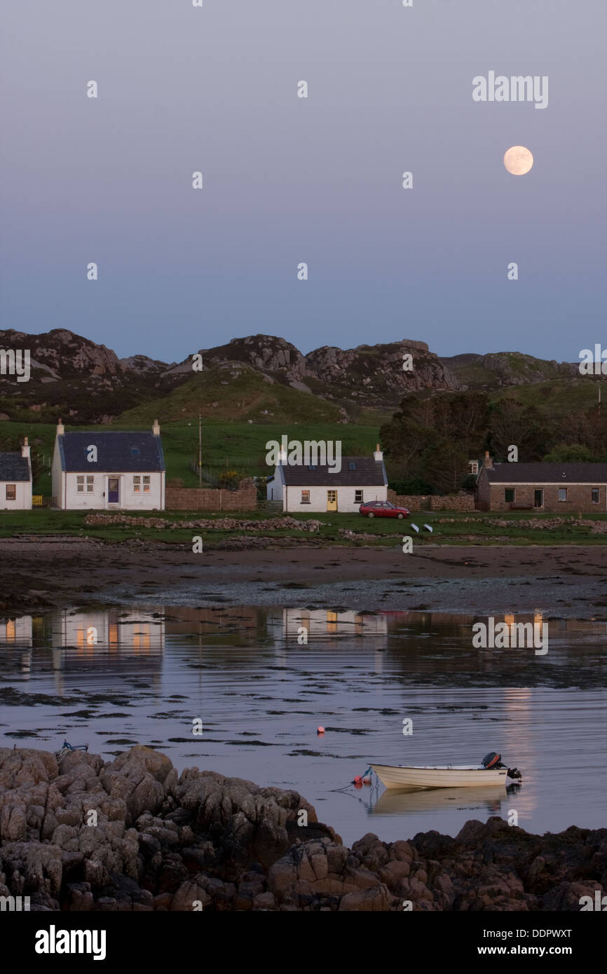 Rocky inlet harbour of Kintra, Isle of Mull at sunset, with full moon rising Stock Photo