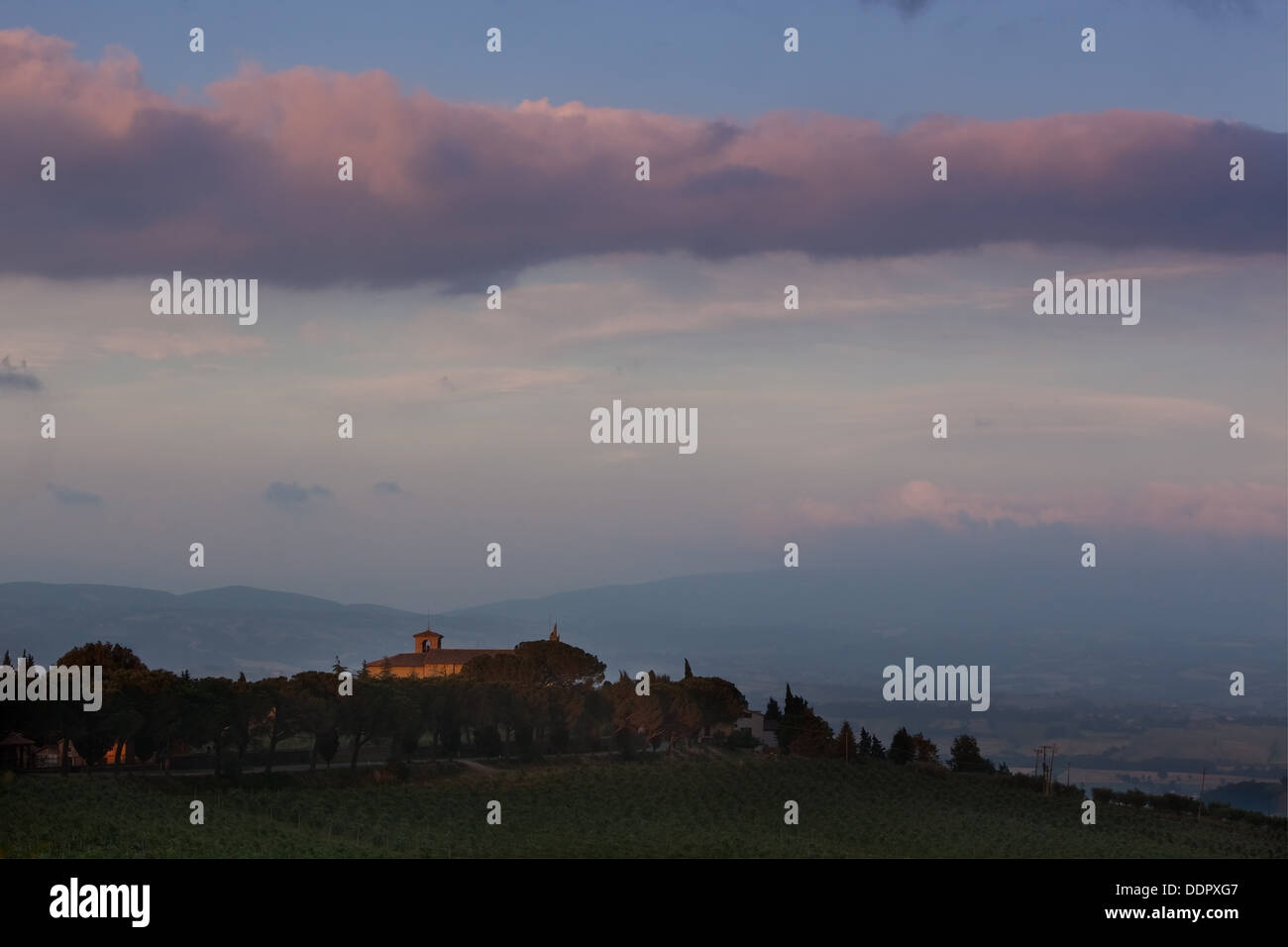 Italian rural abbey at sunset, with spectacular cloud formation, vineyards on sloping hills of foreground Stock Photo