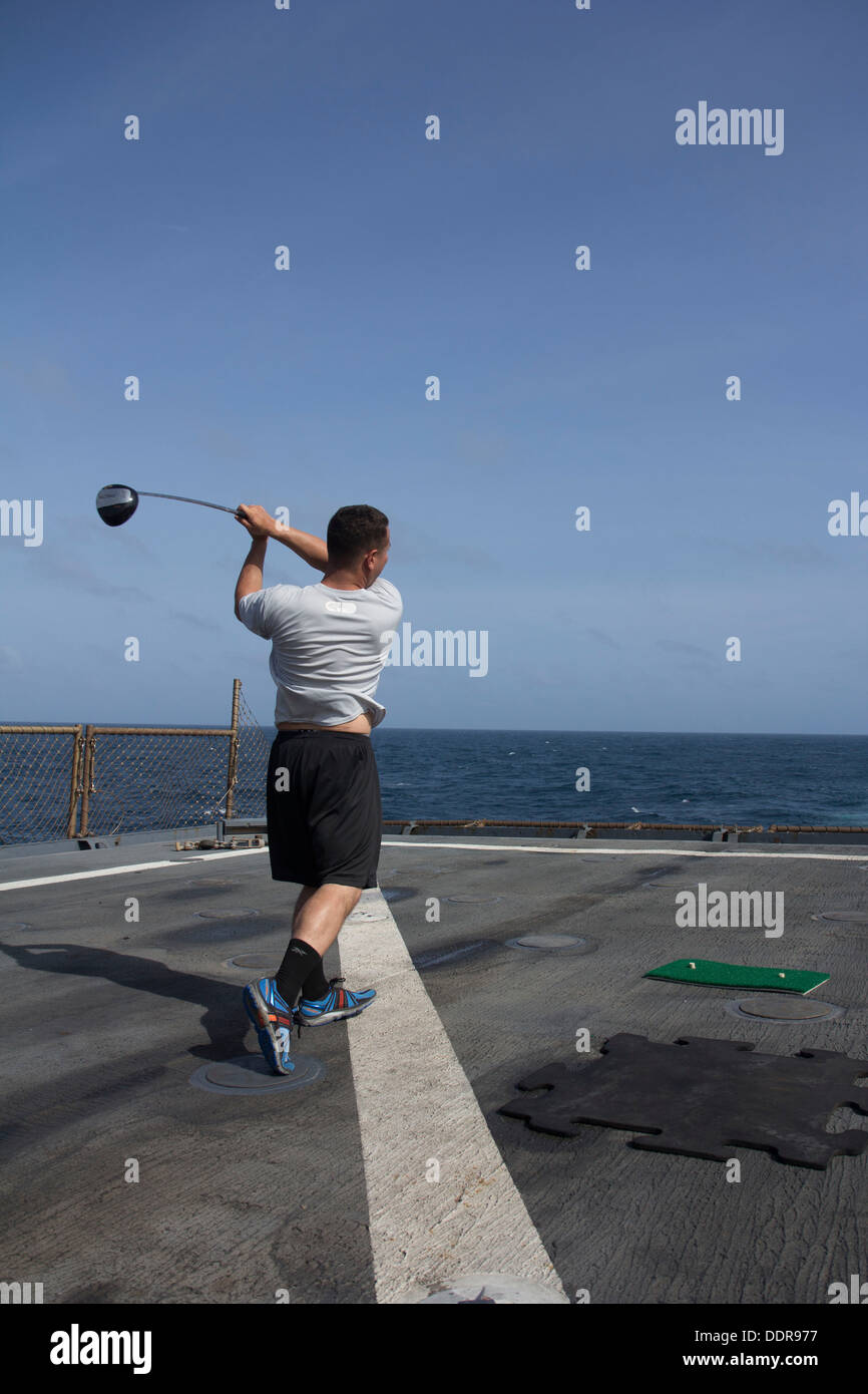 U.S. Marine Corps Lance Cpl. Jason Holman, team leader from Finksburg, Md., assigned to Company K, Battalion Landing Team 3/2, 26th Marine Expeditionary Unit (MEU), hits a golf ball off the flight deck of the USS Carter Hall (LSD 50) during a cookout whil Stock Photo