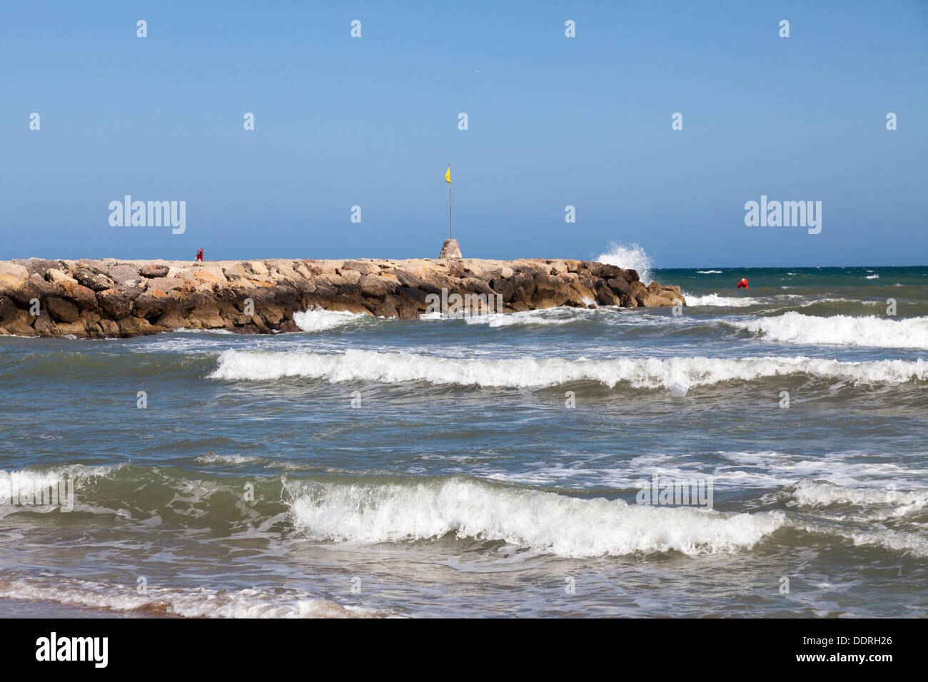 Sea wall stone groyne with breaking waves Stock Photo