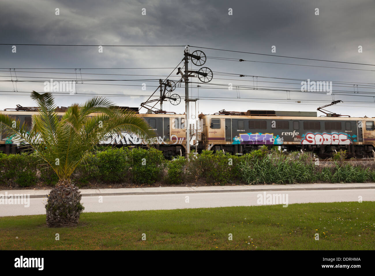 grafiti covered renfe train with overhead power lines Stock Photo