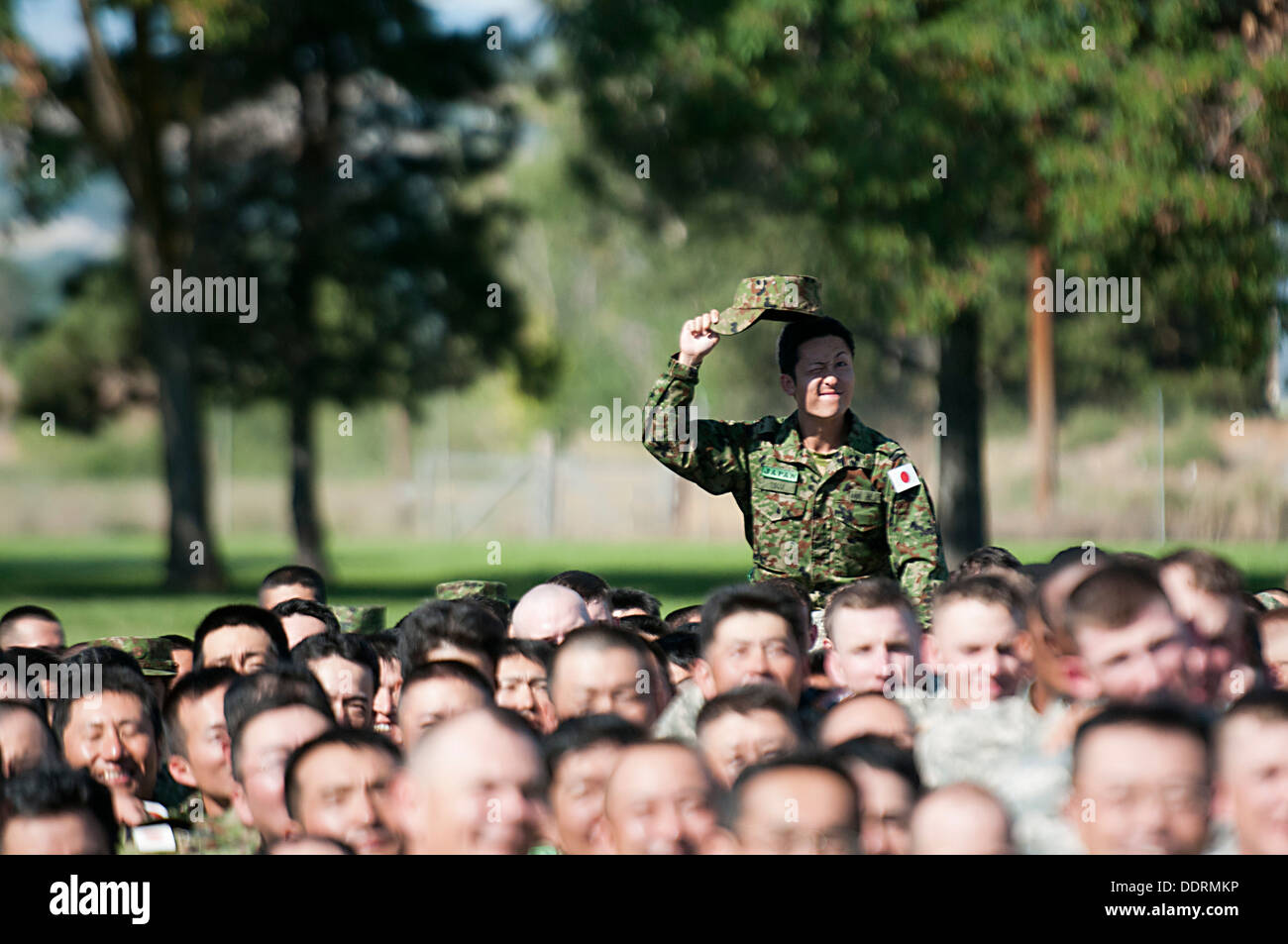 A soldier from 16th Japan Ground Self-Defense Force Regimental Combat Team, 4th Division, raises his hat while sitting on the shoulders of a fellow soldier during a group photo following the opening ceremony for Operation Rising Thunder Sept. 4 at the Yak Stock Photo