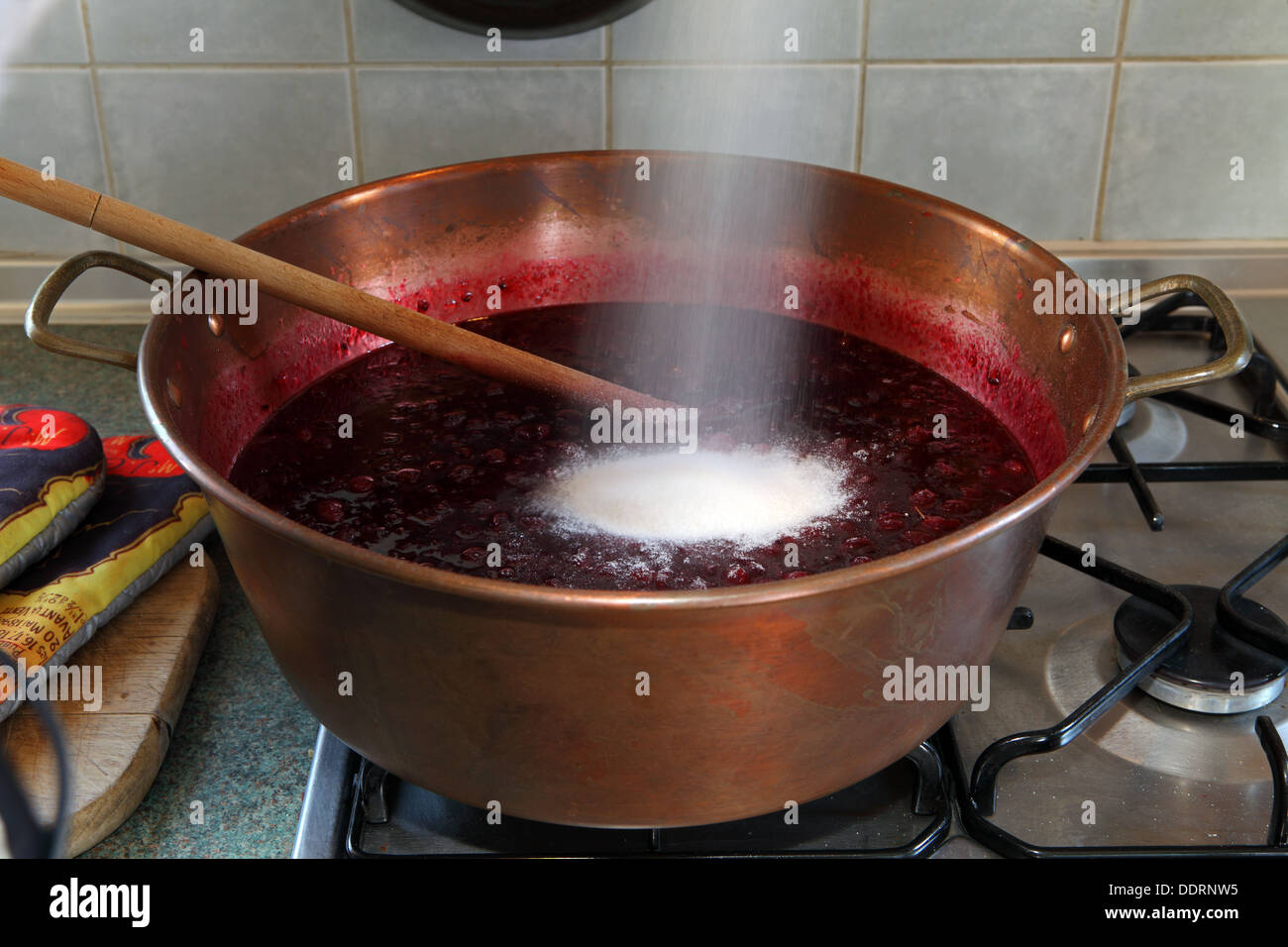Preserving sugar being poured into a pan with fruit for jam making Stock Photo