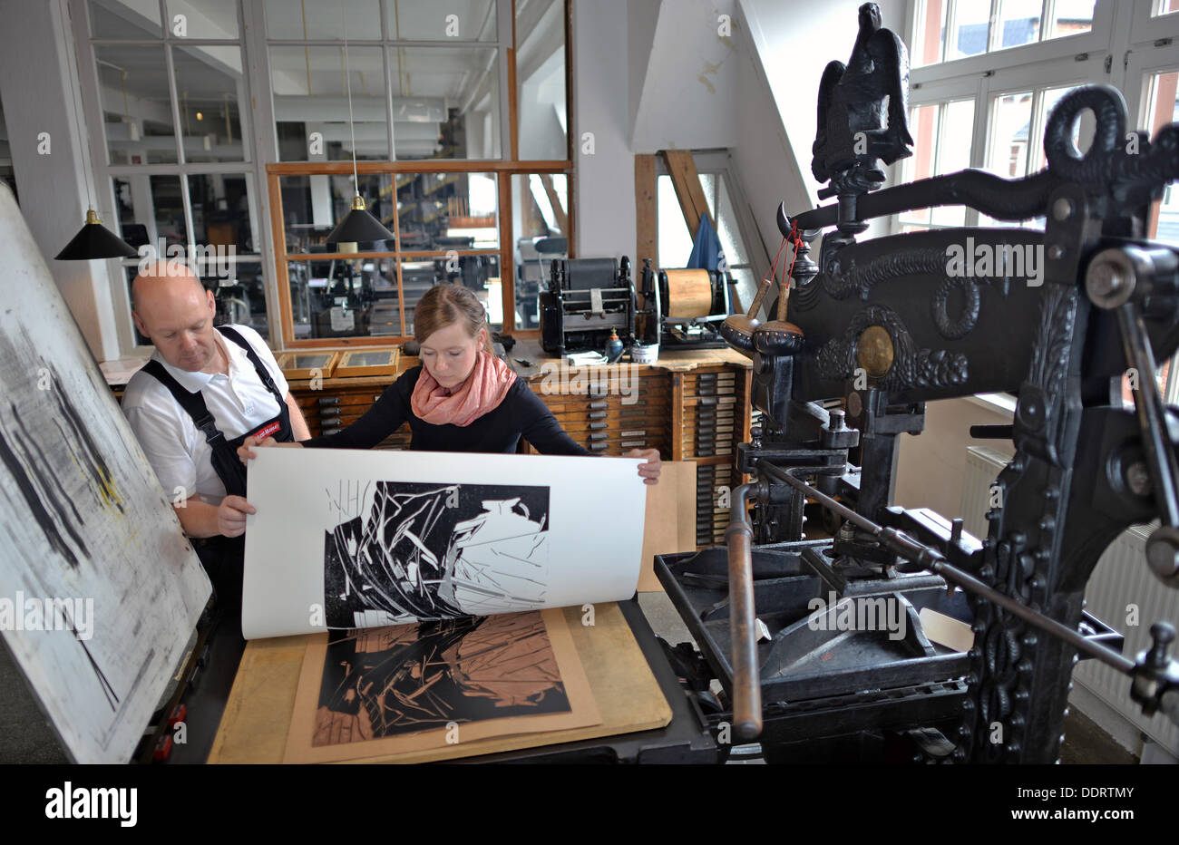 The artist Ellen Moeckel and the typesetter and museum employee, Thomas Kurz, print a linoleum cut on an English knuckle joint press in Leipzig, Germany, 04 September 2013. The 500-year-old historical print workshop and museum with about 100 working machines and presses presents its unique concept of being a producing workshop and a museum at the same time on the countrywide Heritage Open Day on 08 September 2013. Photo: HENDRIK SCHMIDT Stock Photo