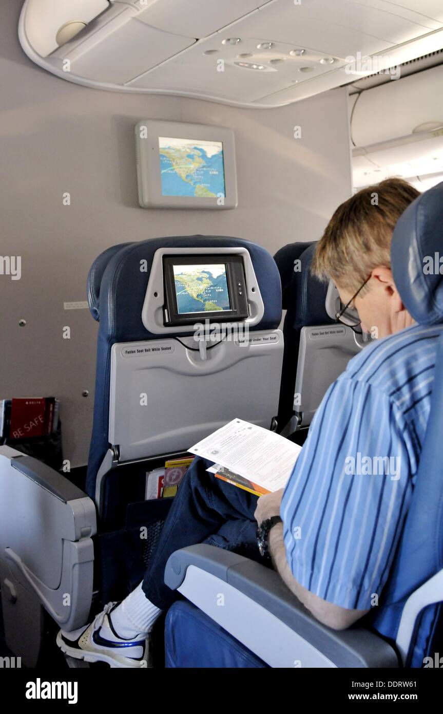 Passenger on commercial airplane reading map of destination on screen Stock Photo