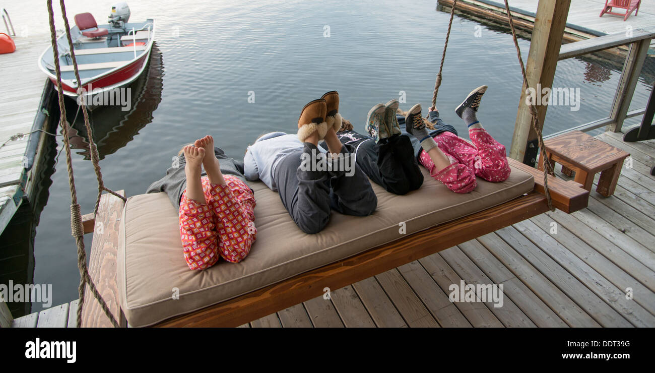 Three girls enjoying on swing chair at a dock, Lake Of The Woods