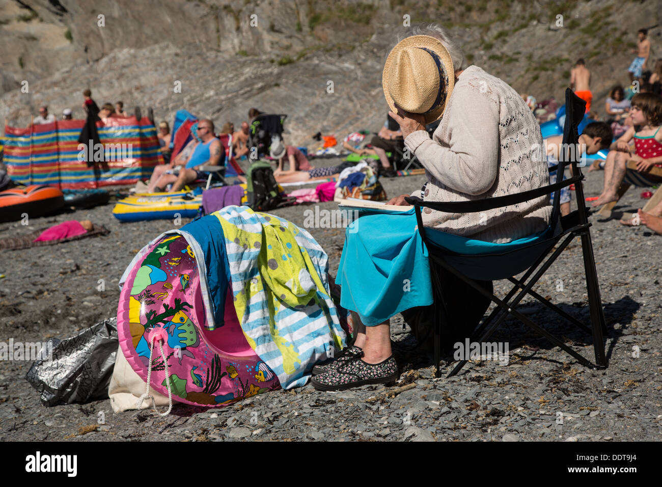 Elderly Lady reading her Book at The Tunnels Beaches, Ilfracombe, Devon Stock Photo
