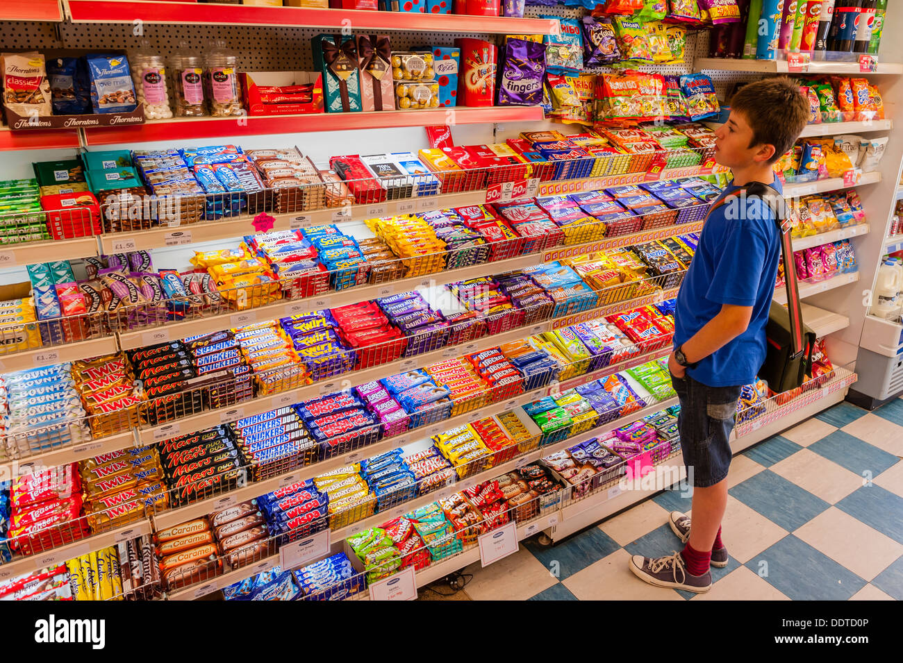A 13 year old boy choosing some sweets in a shop store in the Uk Stock Photo