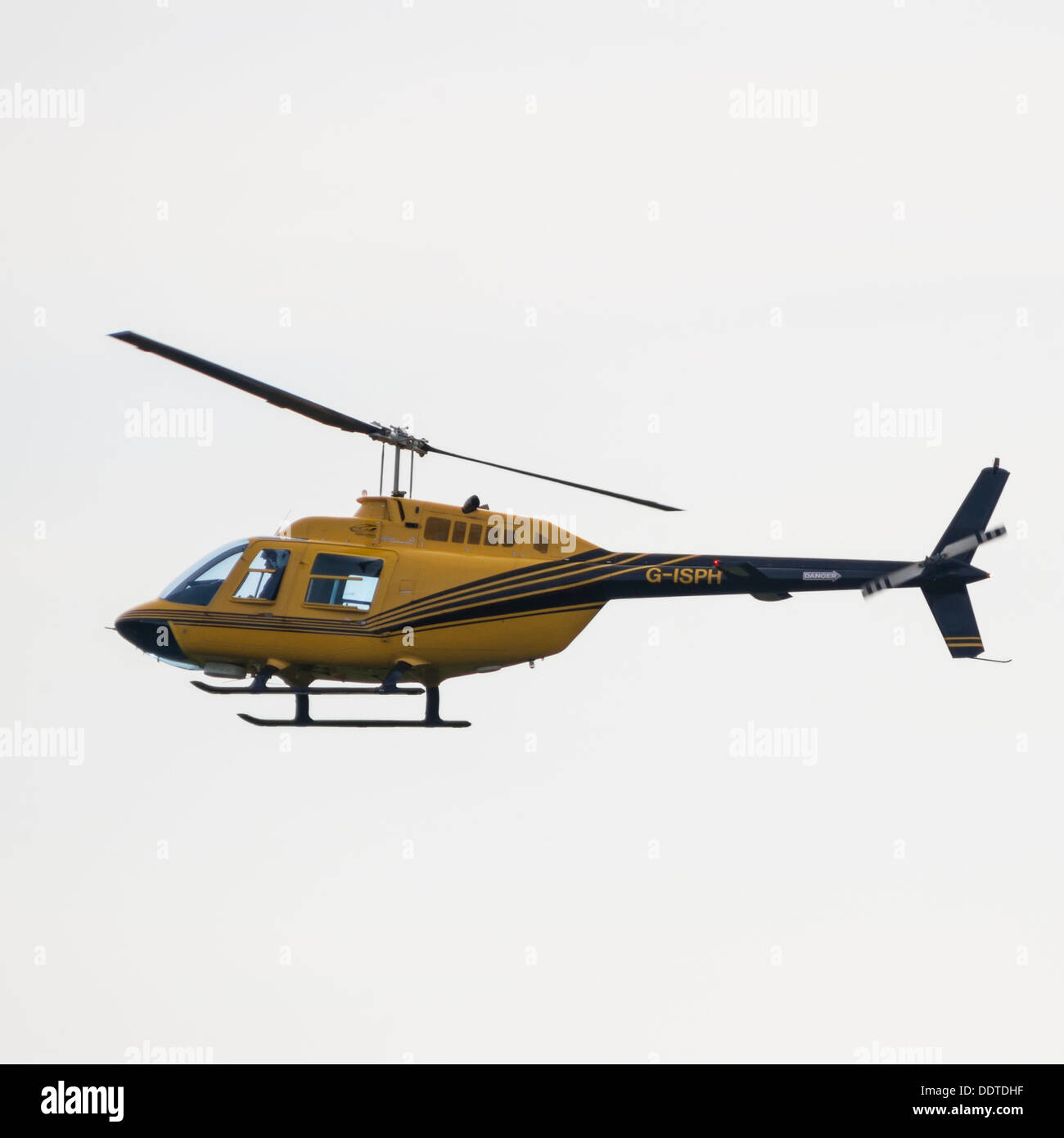 A yellow and black helicopter showing movement as it flys in the Uk Stock Photo