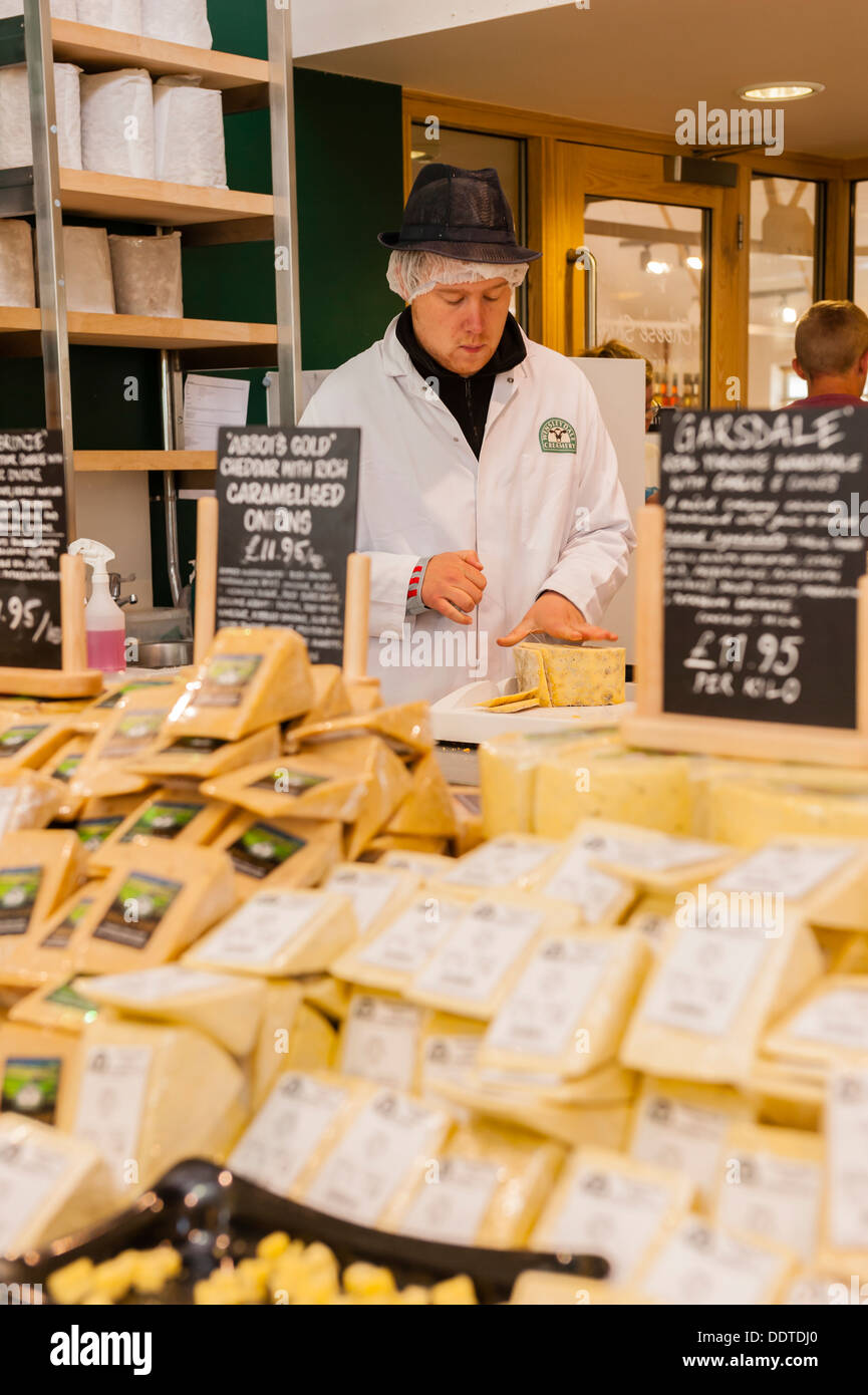 A man cutting cheese in The cheese shop in the Wensleydale Creamery visitor centre in Hawes in Wensleydale Stock Photo