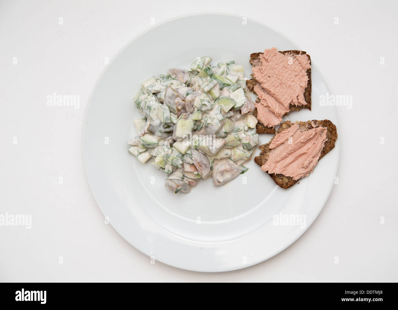 Salad with cucumbers tomatoes on a white plate with spread sandwich made of wheat and sourdough bread with turkey Stock Photo