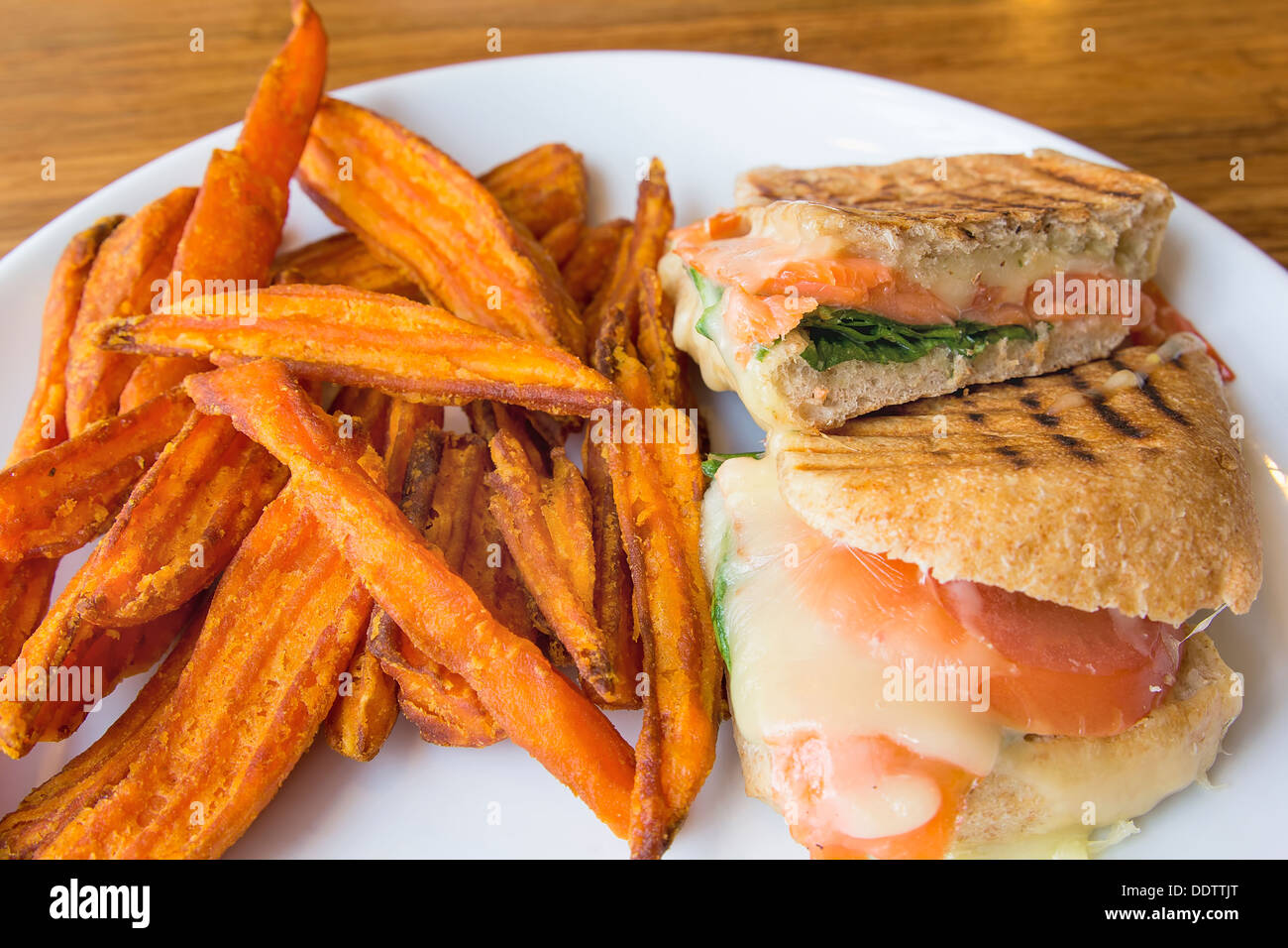 Smoked Salmon Panini Spinach Tomato Mozzarella Cheese Pesto Mayo and Sweet Potato Fries Closeup Stock Photo