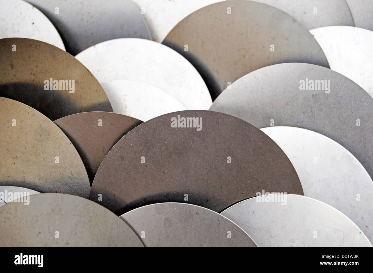 Silver disks stacked and reflecting different light. Stock Photo