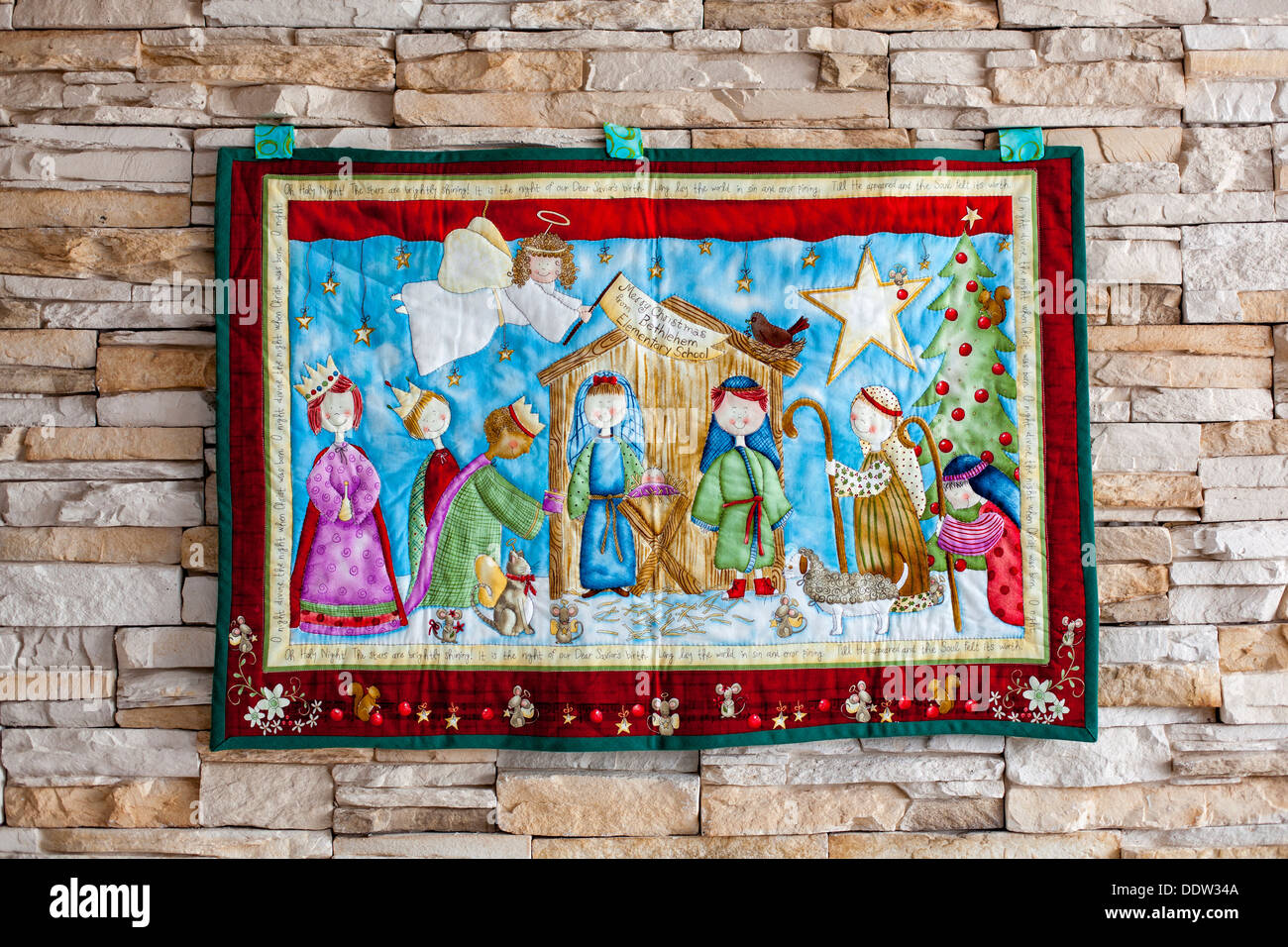 Colored Christmas tapestry hanging from a stone wall Stock Photo