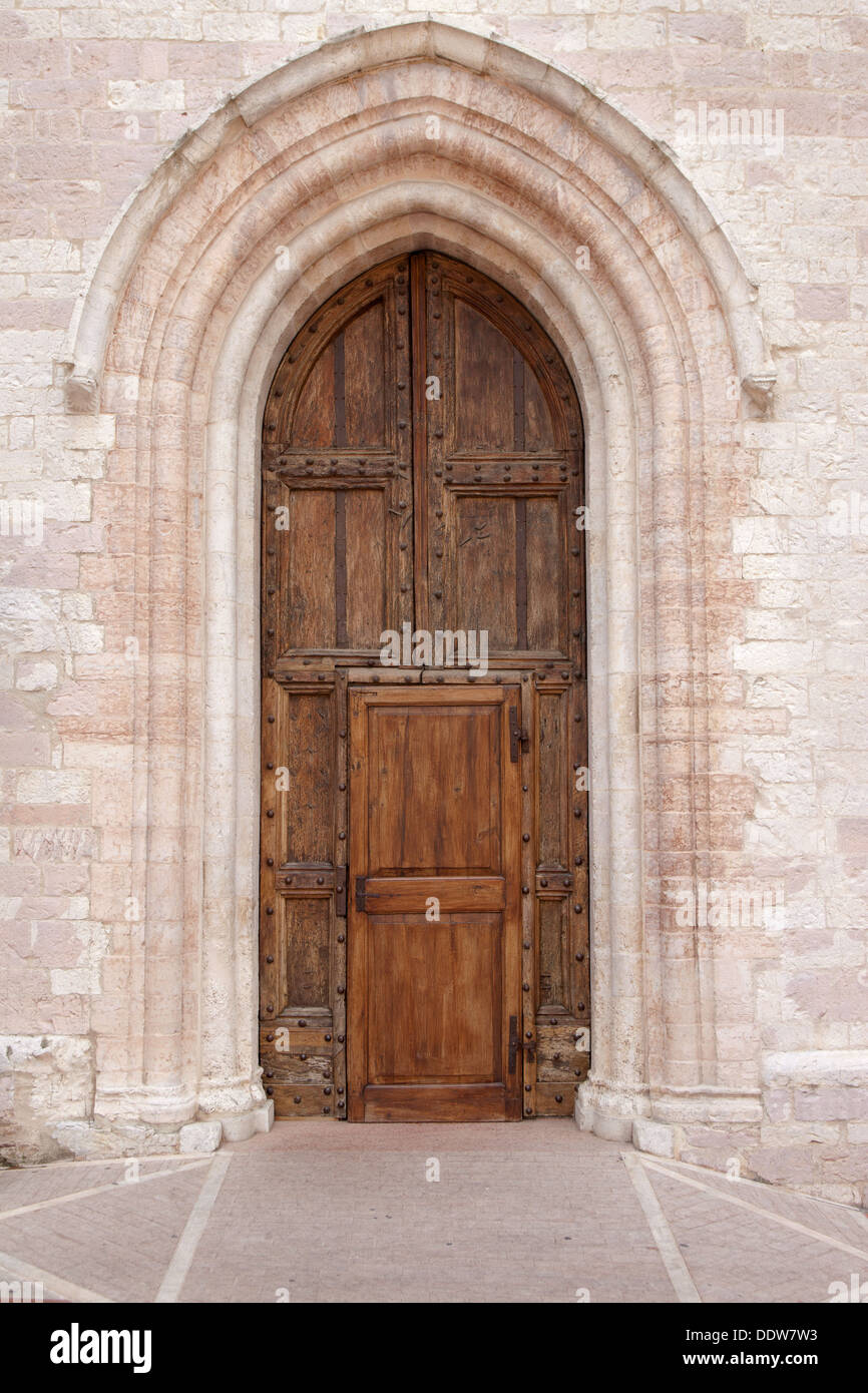 View of old double wooden arched door, with central rectangular entrance, of Santa Chiara church, with patterned pavimenti entra Stock Photo
