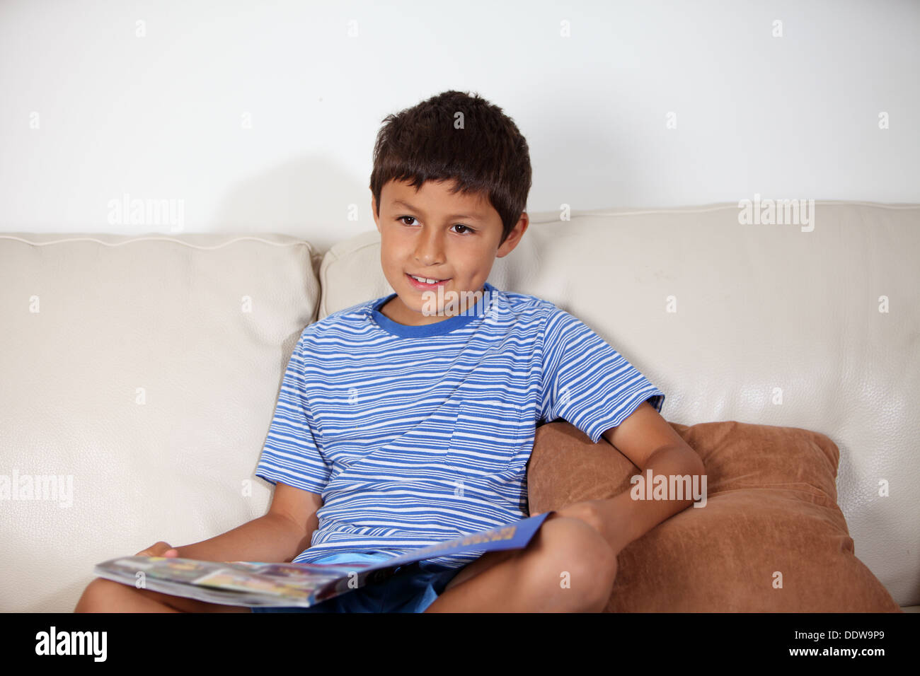 Young boy on the sofa reading a magazine Stock Photo